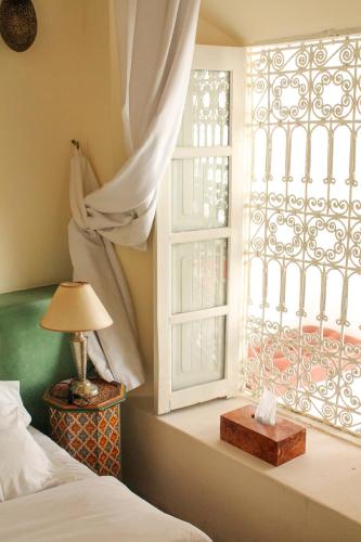 a bedroom with a window and a bed and a lamp at Riad Tizwa Marrakech in Marrakech