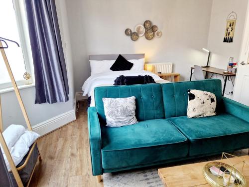 a living room with a green couch and a bed at West Beck House Newcastle - Spacious Double Room in Newcastle upon Tyne