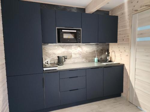 a kitchen with navy blue cabinets and a microwave at Ekosfera Piława Apartamenty z podgrzewanym basenem in Borne Sulinowo