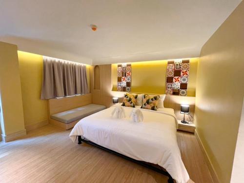 a bedroom with a large white bed and a couch at Kastel Bangkok Hotel in Bangkok