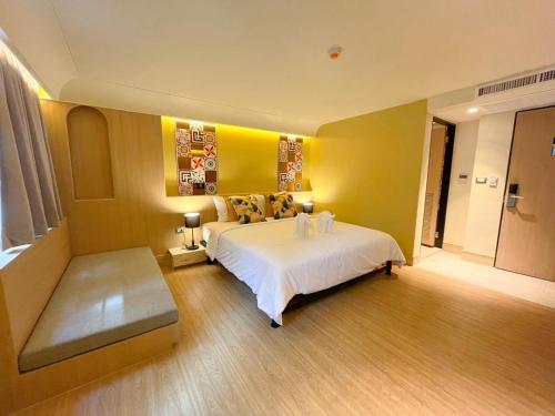 a bedroom with a white bed and a yellow wall at Kastel Bangkok Hotel in Bangkok