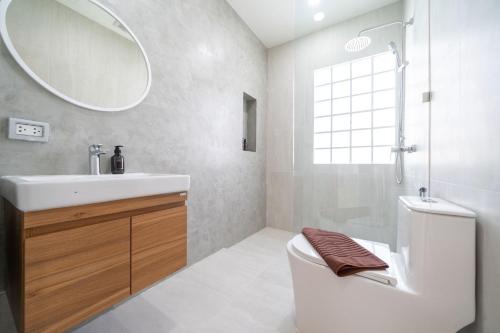 Un baño con lavabo, inodoro y espejo. en Brand New 4BR Balinese Style Pool Villa Kaia just 5 min drive from NaiHarn Beach, en Rawai Beach