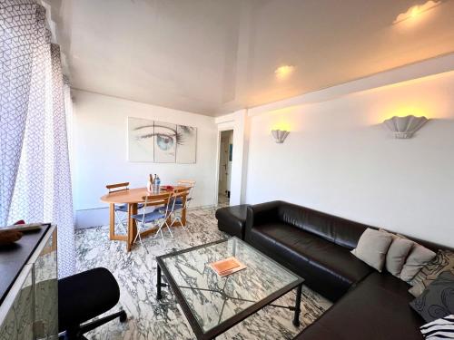 un salon avec un canapé en cuir noir et une table dans l'établissement A077 Appartement agreable avec vue mer et palais des festivals, à Cannes