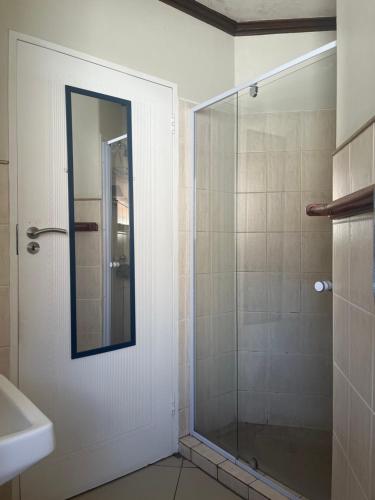 a bathroom with a glass shower with a mirror at Centurion Family House in Centurion