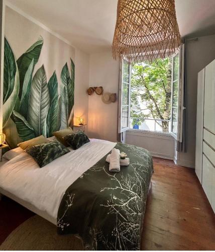 - une chambre avec un grand lit orné d'une fresque murale représentant de grandes feuilles dans l'établissement LE BOTANICA Bel appartement situé à 5 min de la gare d'Angers, à Angers