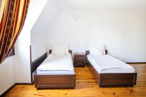 two beds in a room with wooden floors at Pałac Krobielowice in Kąty Wrocławskie
