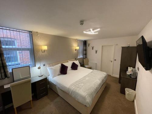 a bedroom with a bed and a desk with a computer at Ruskin Hotel in Blackpool