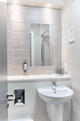 a white bathroom with a sink and a mirror at The Lodge Hotel in Newbury