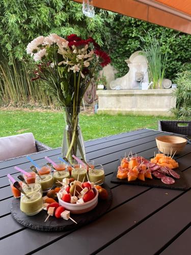 a table with a tray of food and a vase of flowers at Chambres d'hôtes Naturiste Les Trois Pins in Tourtrol