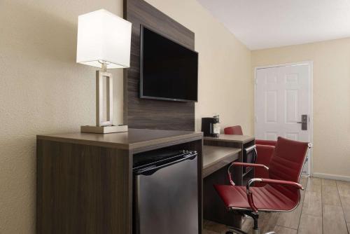 a hotel room with a desk with a television and a chair at Ramada by Wyndham Kingman in Kingman