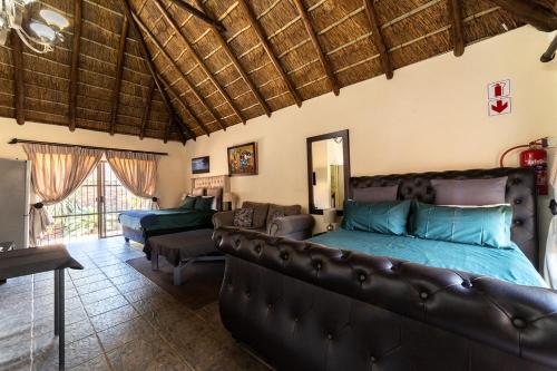 a living room with a couch and a bed at Thatch Haven Guesthouse in Centurion
