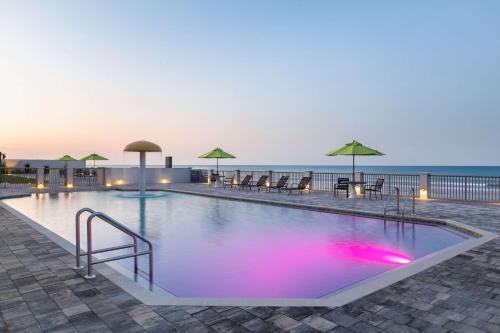 a large swimming pool with the ocean in the background at La Quinta by Wyndham Oceanfront Daytona Beach in Daytona Beach