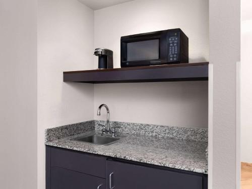 a kitchen with a sink and a microwave on a shelf at La Quinta by Wyndham Santa Clarita - Valencia in Stevenson Ranch
