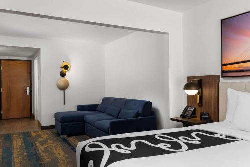 a hotel room with a bed and a blue couch at La Quinta by Wyndham Kennewick in Kennewick