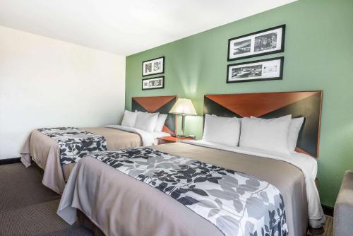 two beds in a hotel room with green walls at Sleep Inn & Suites University-Shands in Gainesville