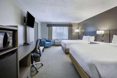 a hotel room with two beds and a flat screen tv at Days Inn & Suites by Wyndham Moncton in Moncton
