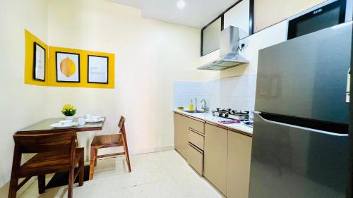 a kitchen with a table and a stainless steel refrigerator at BluO Studio - M Block Mkt Greater Kailash in New Delhi