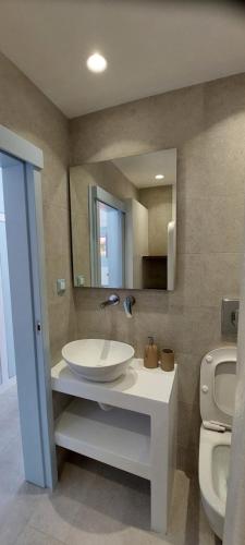 a bathroom with a sink and a toilet and a mirror at Traditional dream myconian studio in Ornos