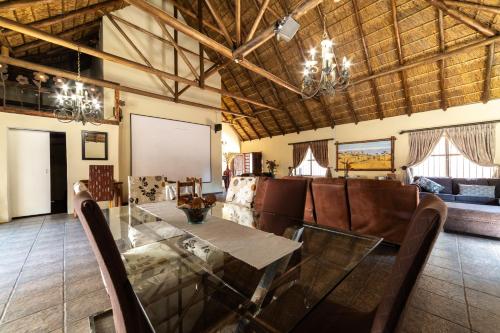 a dining room with a glass table and leather chairs at Thatch Haven Guesthouse in Centurion