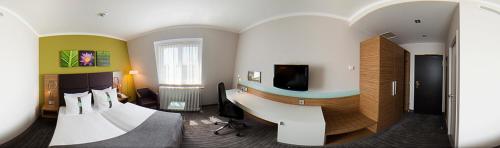 a hotel room with a bed and a desk with a television at Willow Hotel Restaurant in Kötschlitz