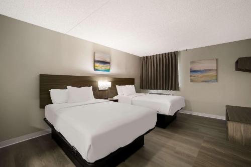 a hotel room with two beds and a television at Suburban Studios Milwaukee Airport in Milwaukee