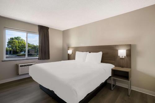 a large white bed in a room with a window at Suburban Studios Milwaukee Airport in Milwaukee