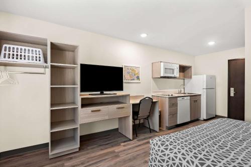 a room with a bed and a desk with a television at WoodSpring Suites Savannah West Chatham Parkway in Savannah