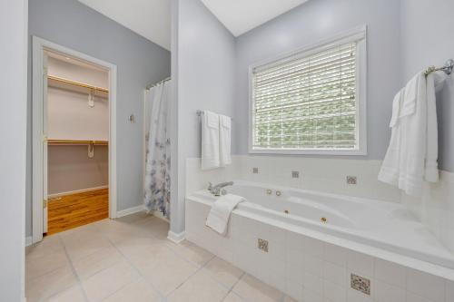 a white bathroom with a tub and a window at Modern Lake Acess Retreat, Hot Tub, Pet Friendly! in Huddleston