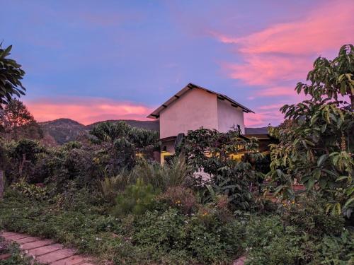 a house on a hill with a sunset in the background at Ivy Coffee Farm - Garden House in Ðưc Trọng