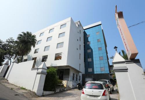 a white building with a car parked in front of it at Super Townhouse Prince Palace in Trivandrum