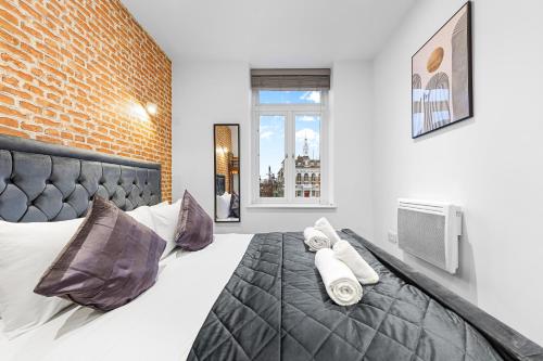 a bedroom with a large bed with a brick wall at Comfy Flat in Staines in Staines upon Thames