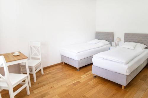 two beds in a room with a table and a desk at Oficyna Krobielowice in Kąty Wrocławskie