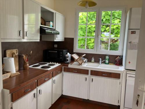 une cuisine avec des armoires blanches, un évier et une cuisinière dans l'établissement Maison à Vaux-sur-Mer, à Vaux-sur-Mer