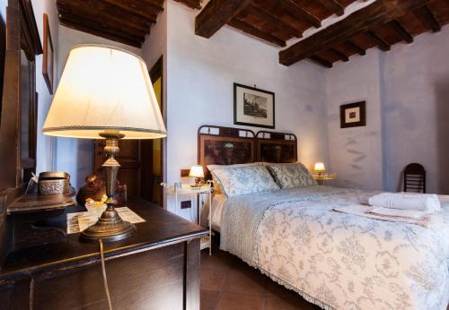 a bedroom with a bed and a table with a lamp at Borgo Tepolini Country House in Castel del Piano
