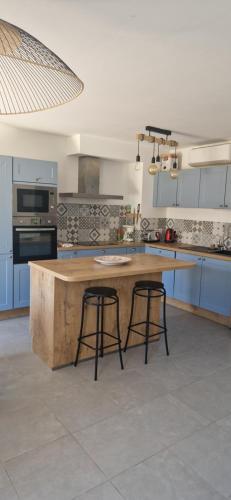 une cuisine avec un grand îlot en bois et deux tabourets de bar dans l'établissement Maison Pierres de Provence, à Saint-Cannat