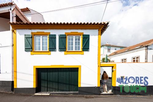 a white house with yellow trim and a dog standing in front of it at Casa dos Rios in Angra do Heroísmo