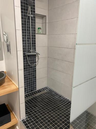 a shower with a black and white tiled floor at O Soleya in Saint-Joseph