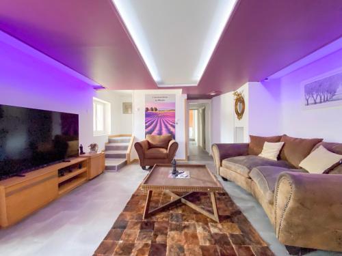 a living room with purple ceilings and a large tv at La grange en pierre - chic & piscine privée in Queyssac