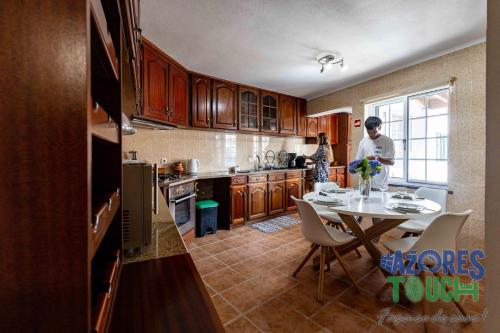 a kitchen with a table and a woman standing in a kitchen at Casa dos Rios in Angra do Heroísmo