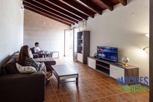 two people sitting in a living room with a tv at Casa dos Rios in Angra do Heroísmo