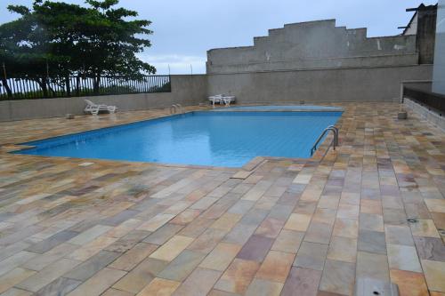 a large swimming pool in a yard with a patio at Apartamento Satel Praia in Itanhaém