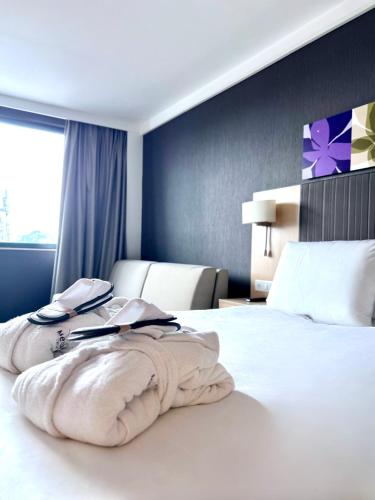 a hotel room with a large white bed and a window at Mercure Valenciennes Centre in Valenciennes