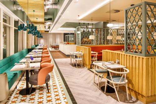 a restaurant with a row of tables and chairs at ibis budget Manchester Airport T2 in Hale