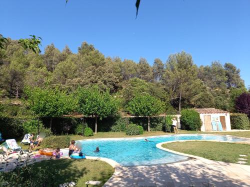 une piscine dans un jardin avec des gens qui jouent dedans dans l'établissement Le Relais Du Grand Logis, à Mirabeau