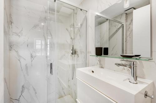 a white bathroom with a shower and a sink at Les Relais du Capitole - Appartements d'hôtes in Toulouse