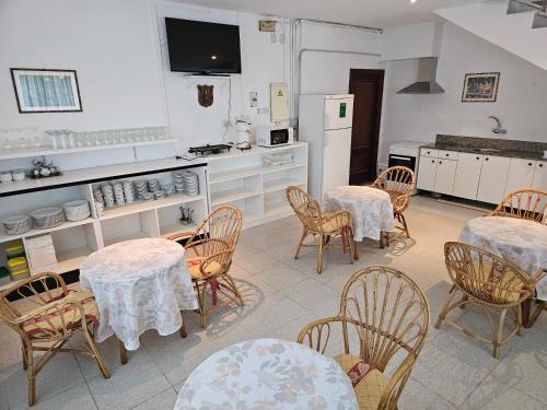 Una cocina con mesas y sillas y una cocina con gabinetes blancos. en Motel Bambú, en Lugo