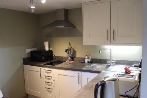 a kitchen with white cabinets and a sink at Parkfields Barns Self Catering Accommodation in Buckingham