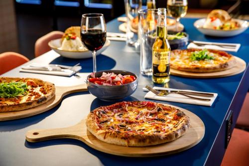a table with three pizzas and a glass of wine at ibis budget Manchester Airport T2 in Hale