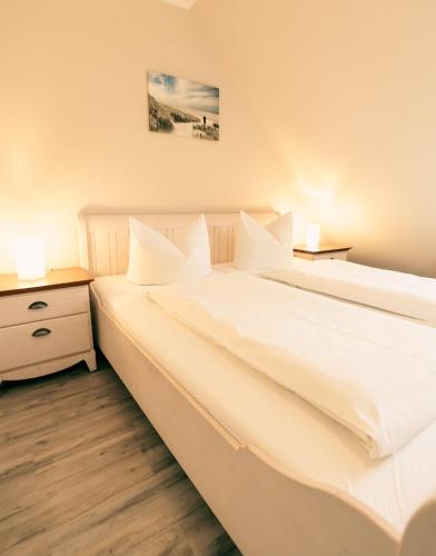 two white beds in a room with two lamps at Haus Seeschwalbe Spiekeroog - Wohnung 12 in Spiekeroog