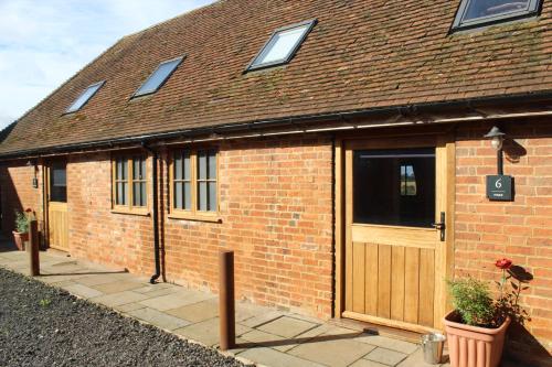 a brick building with a wooden door and a building at Parkfields Barns Self Catering Accommodation in Buckingham